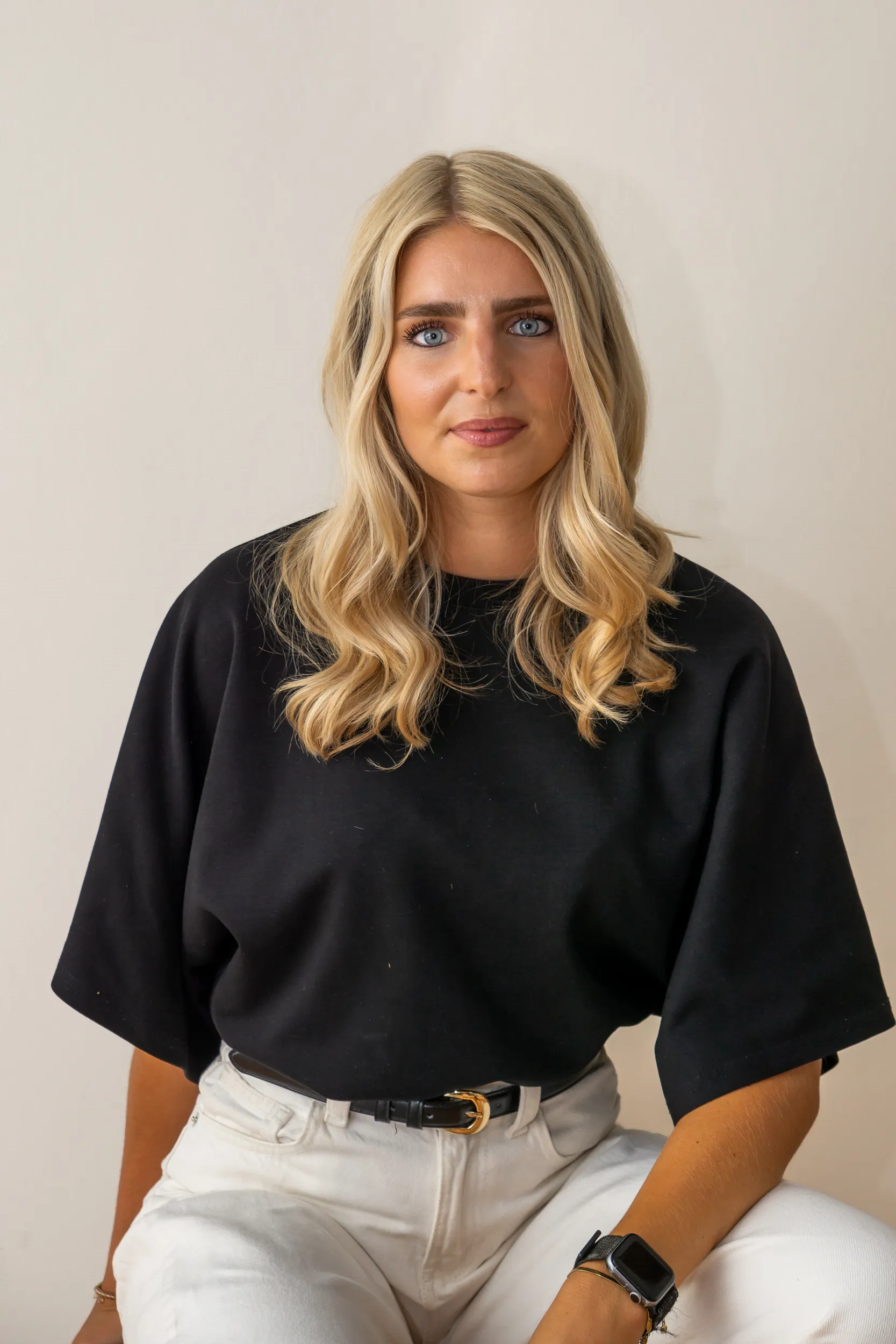 Vrouw in zwart oversized T-shirt en witte broek met een ontspannen houding