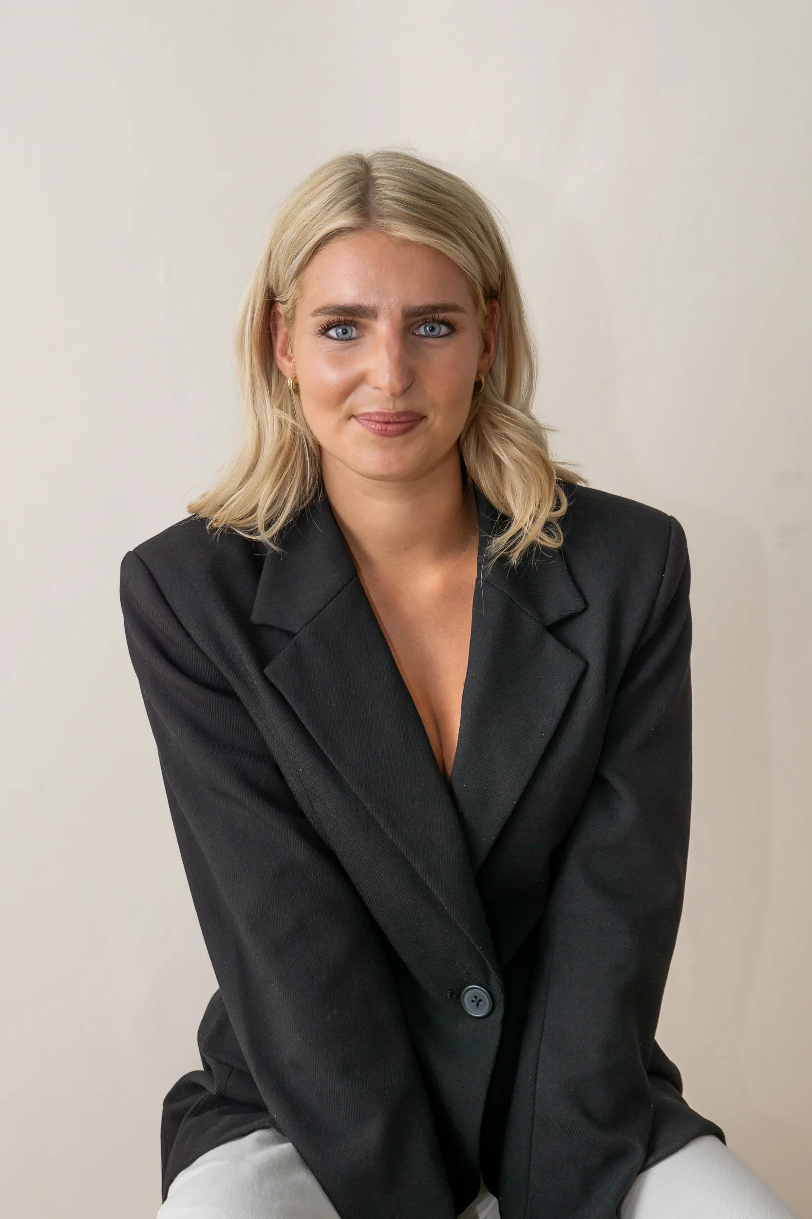 Zittende vrouw in zwarte blazer met een rustige, neutrale blik