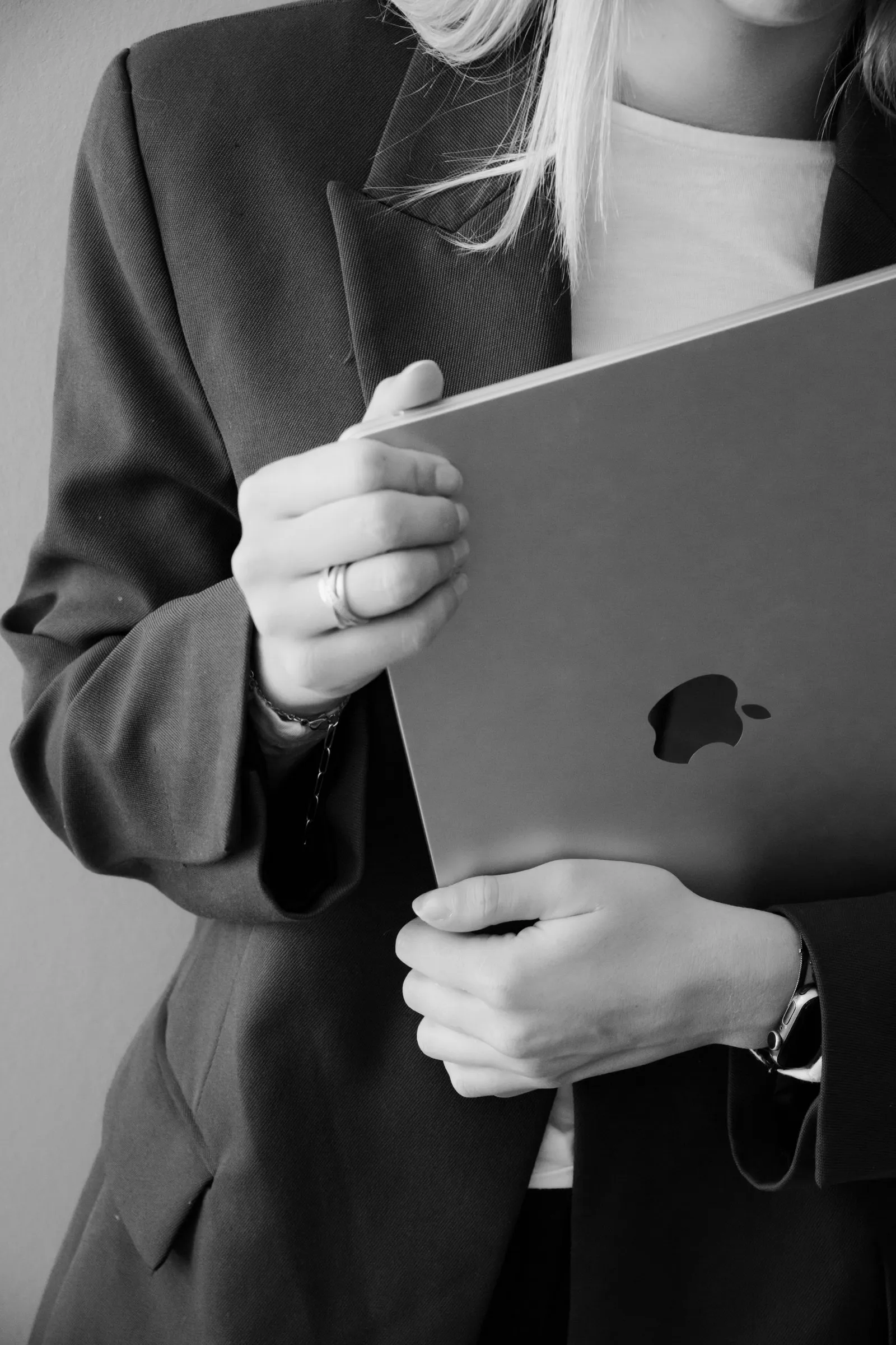 Zwart-wit detail van handen die een laptop tegen het lichaam houden