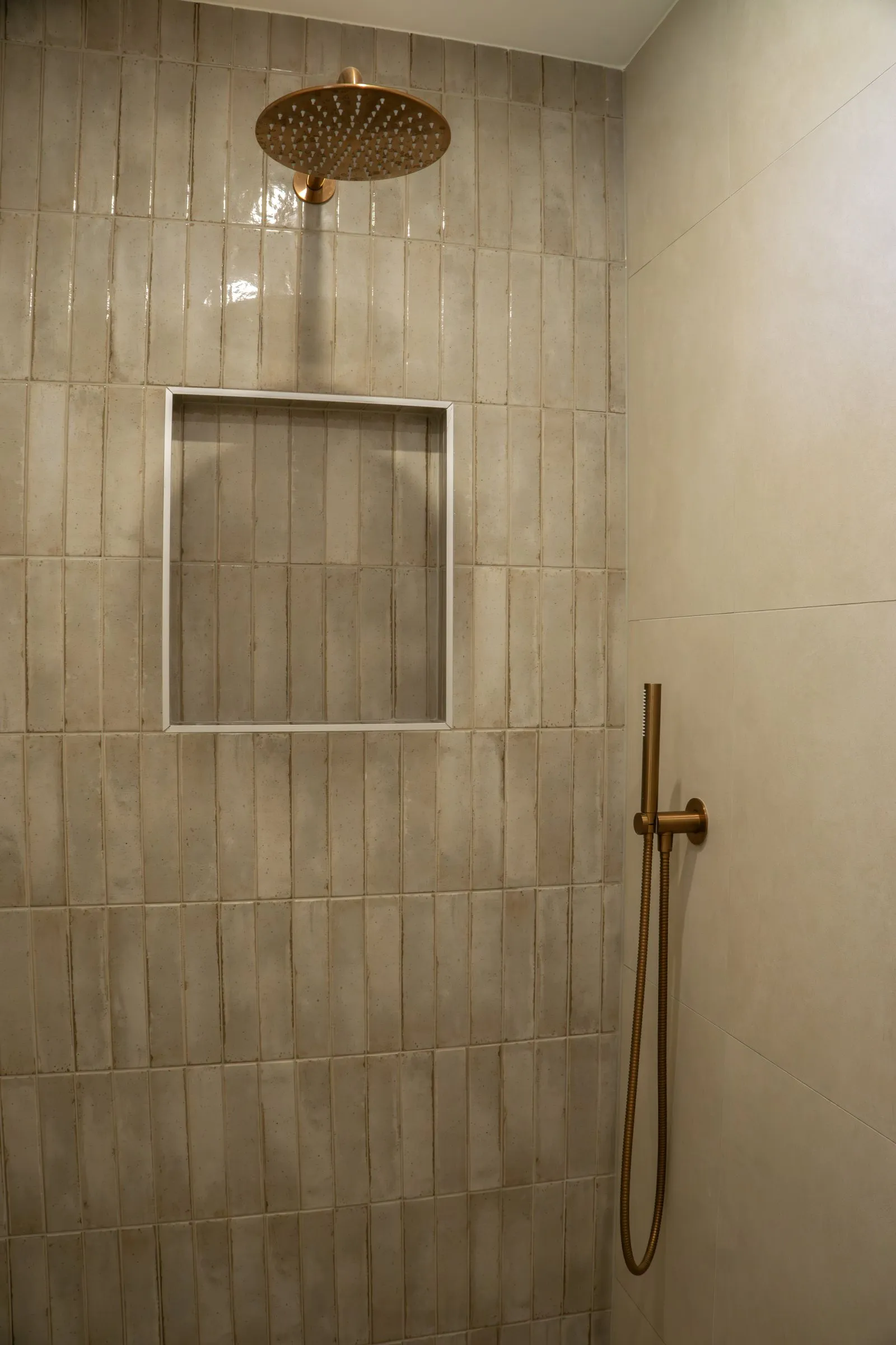 Inloopdouche met beige tegels en messing regendouche
