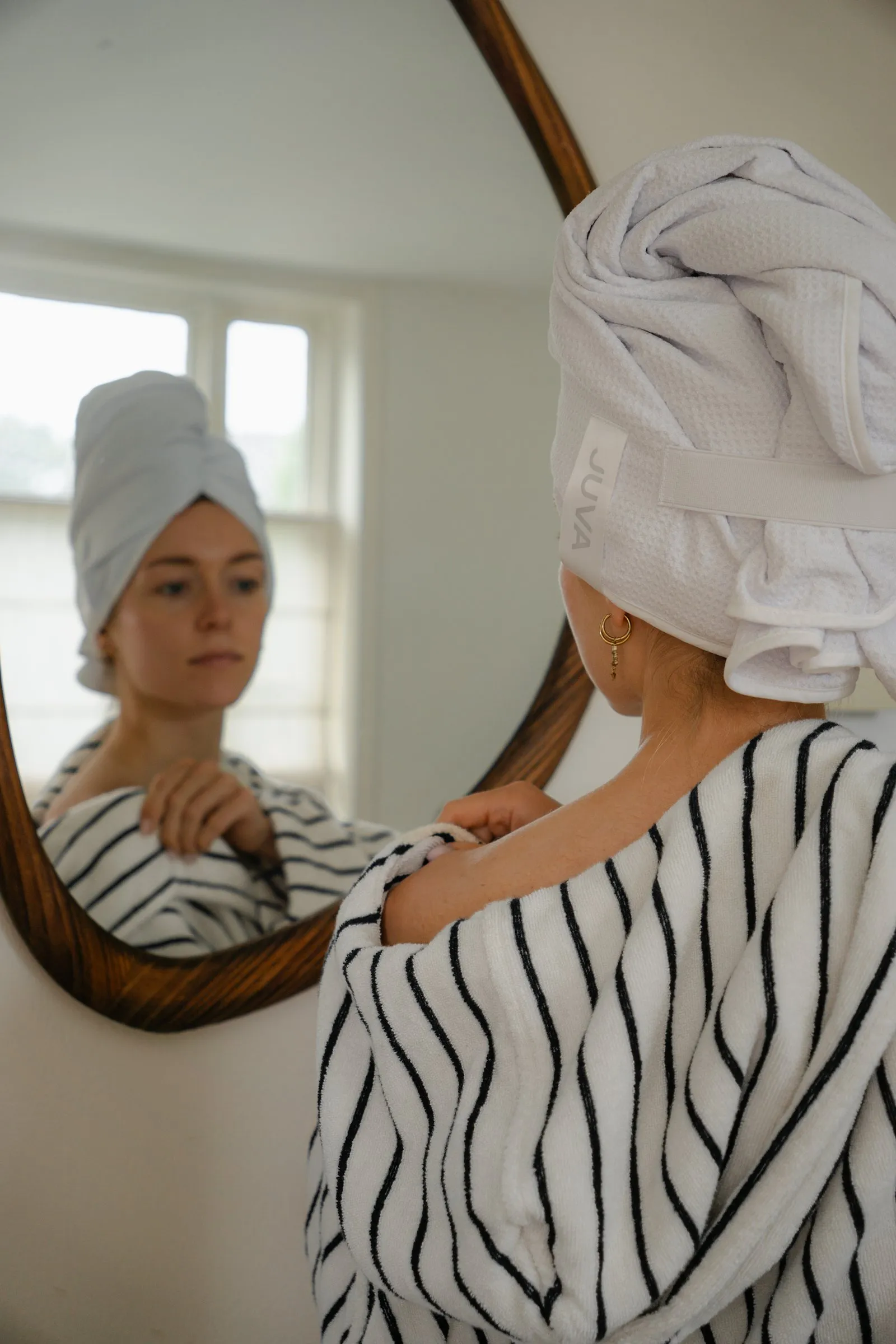 Spiegelbeeld van een vrouw die haar haarhanddoek vastmaakt