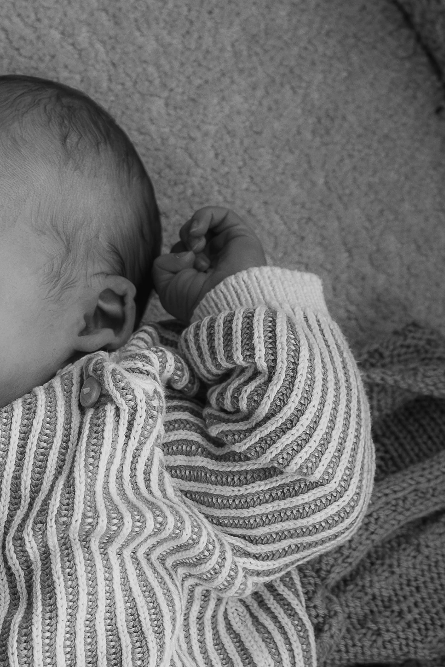 Oor en vuistje van de baby van dichtbij, zwart-wit