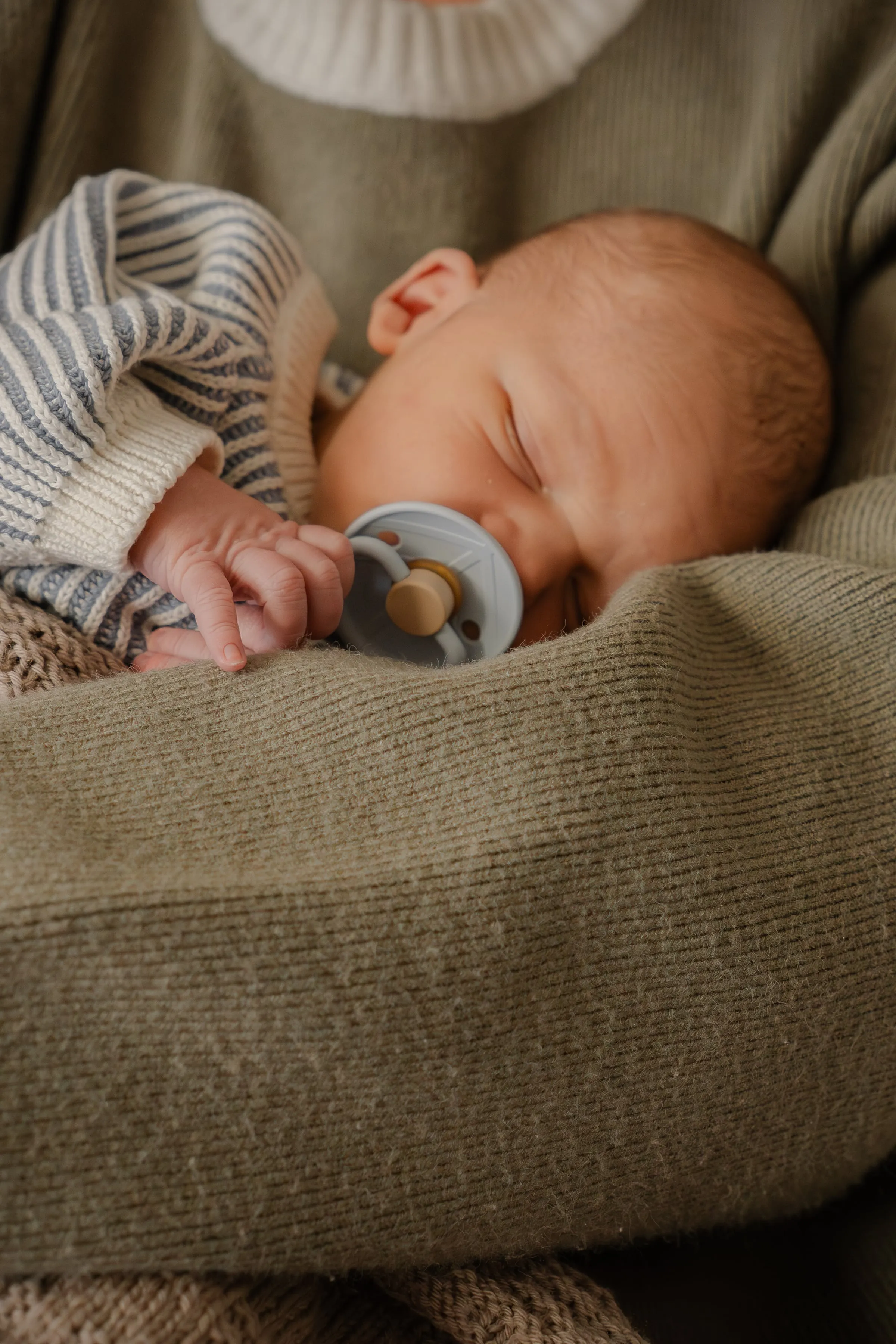 Slapende baby op een olijfgroene deken met speen