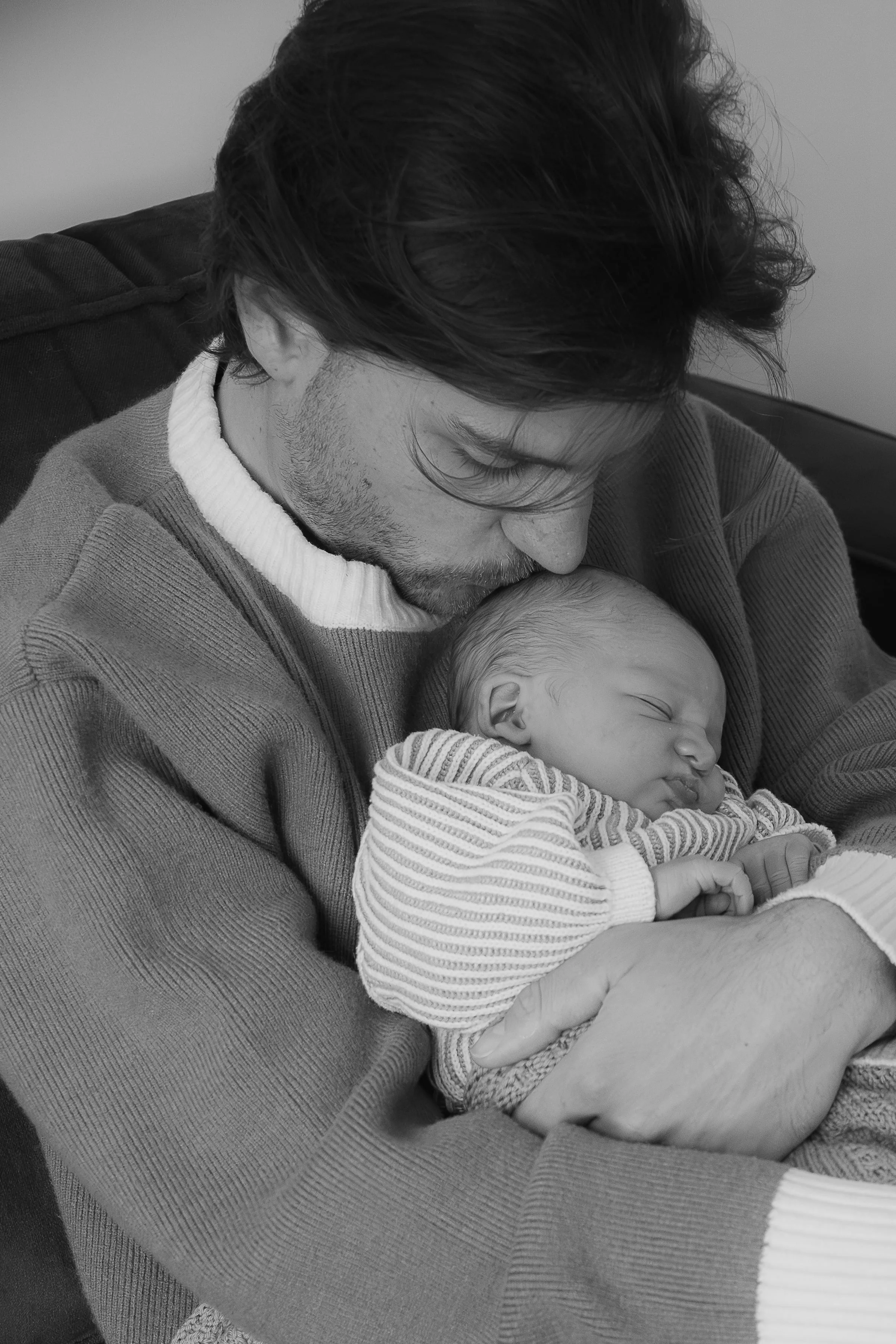 Vader kust het hoofdje van zijn slapende baby, zwart-wit